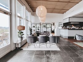 Un interior moderno con una zona de estar, un bar y ventanas amplias.