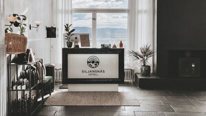 Un mostrador de recepción en el Hotel Siljansnäs, con vistas al cielo y nubes a través de amplias ventanas.