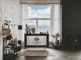 Un mostrador de recepción en el Hotel Siljansnäs, con vistas al cielo y nubes a través de amplias ventanas.