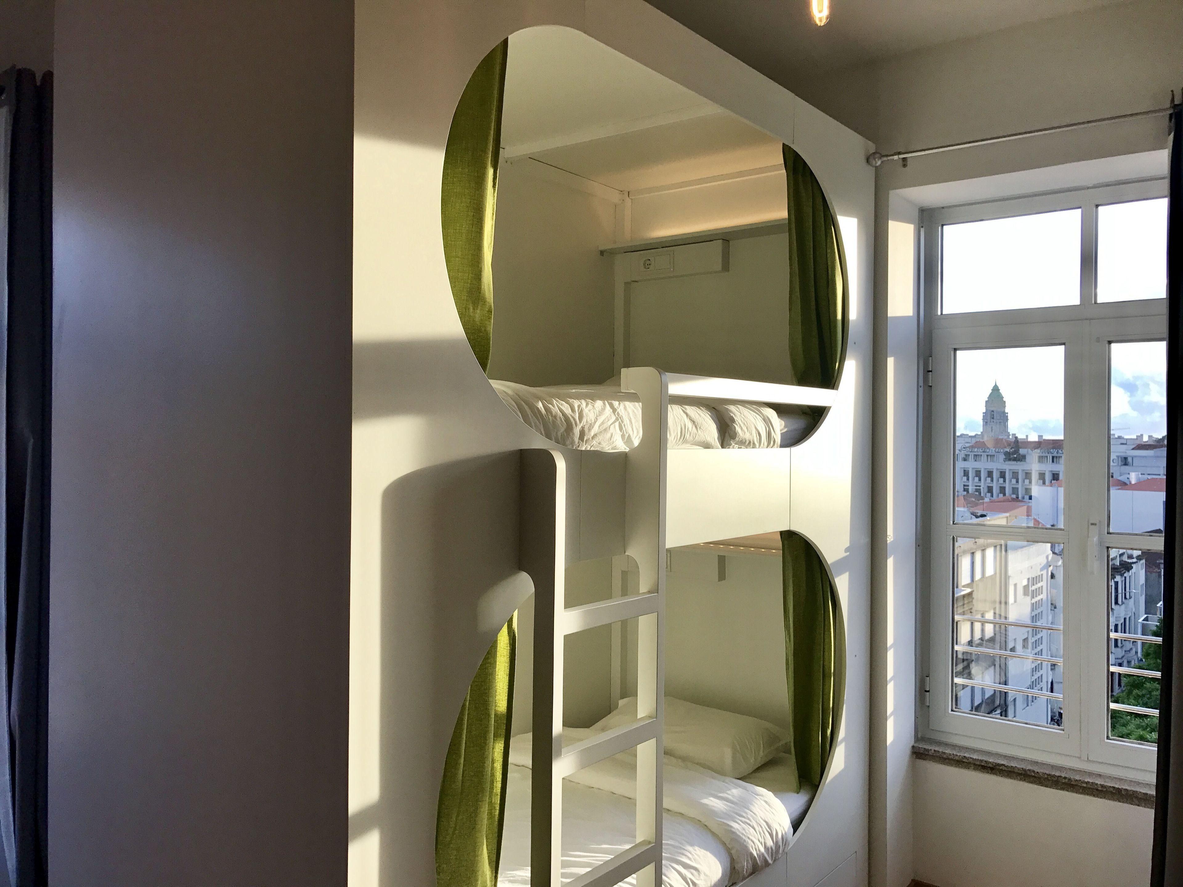 Ein Stockbett mit Blick auf eine Stadtansicht durch ein Fenster.