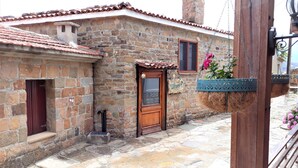 A stone building with a tiled roof, a wooden door, and a window. - Zeydali Hotel (Gökçeada)