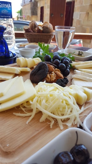 Un plateau de fromages comprenant différents types de fromages, des noix et des raisins.