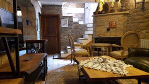 A cozy room with a stone fireplace, wooden furniture, and a television. - Zeydali Hotel (Gökçeada)
