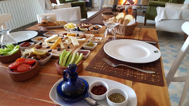 A table set for a meal with various dishes, including cheese, fruits, and nuts. - Zeydali Hotel (Gökçeada)