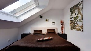 A bedroom with a skylight, a large bed, a nightstand, a wall-mounted artwork, and a small plant. - Pension Haselmann (Münster)
