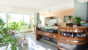 A reception area with a counter, potted plants, and a view of the outside. - Grand Living Place (Bangkok)