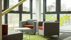A modern interior with large windows, a green carpet, and a staircase. - Peel Park Quarter - Campus Accommodation (Salford)