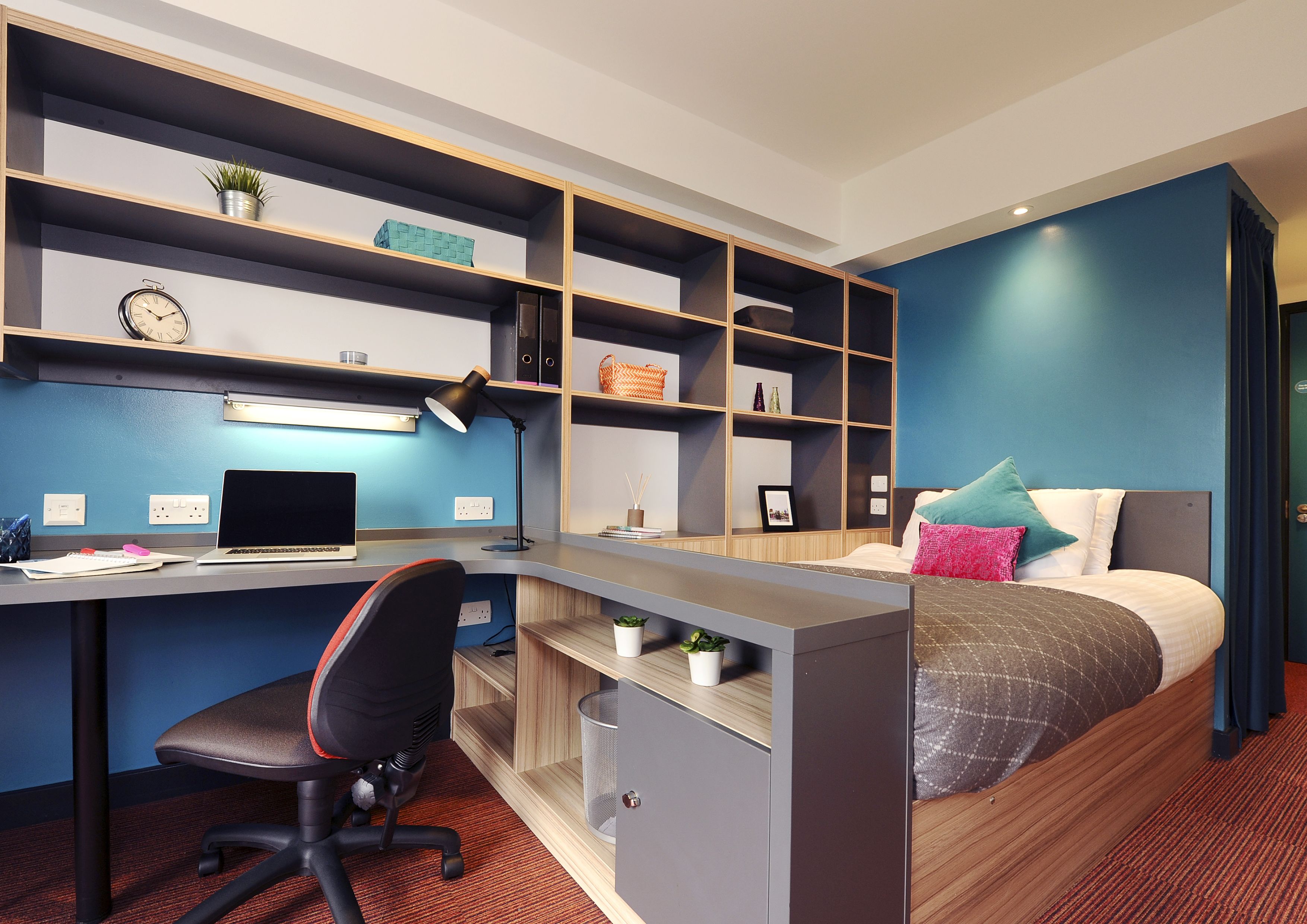 A modern bedroom with a desk, chair, and bed.