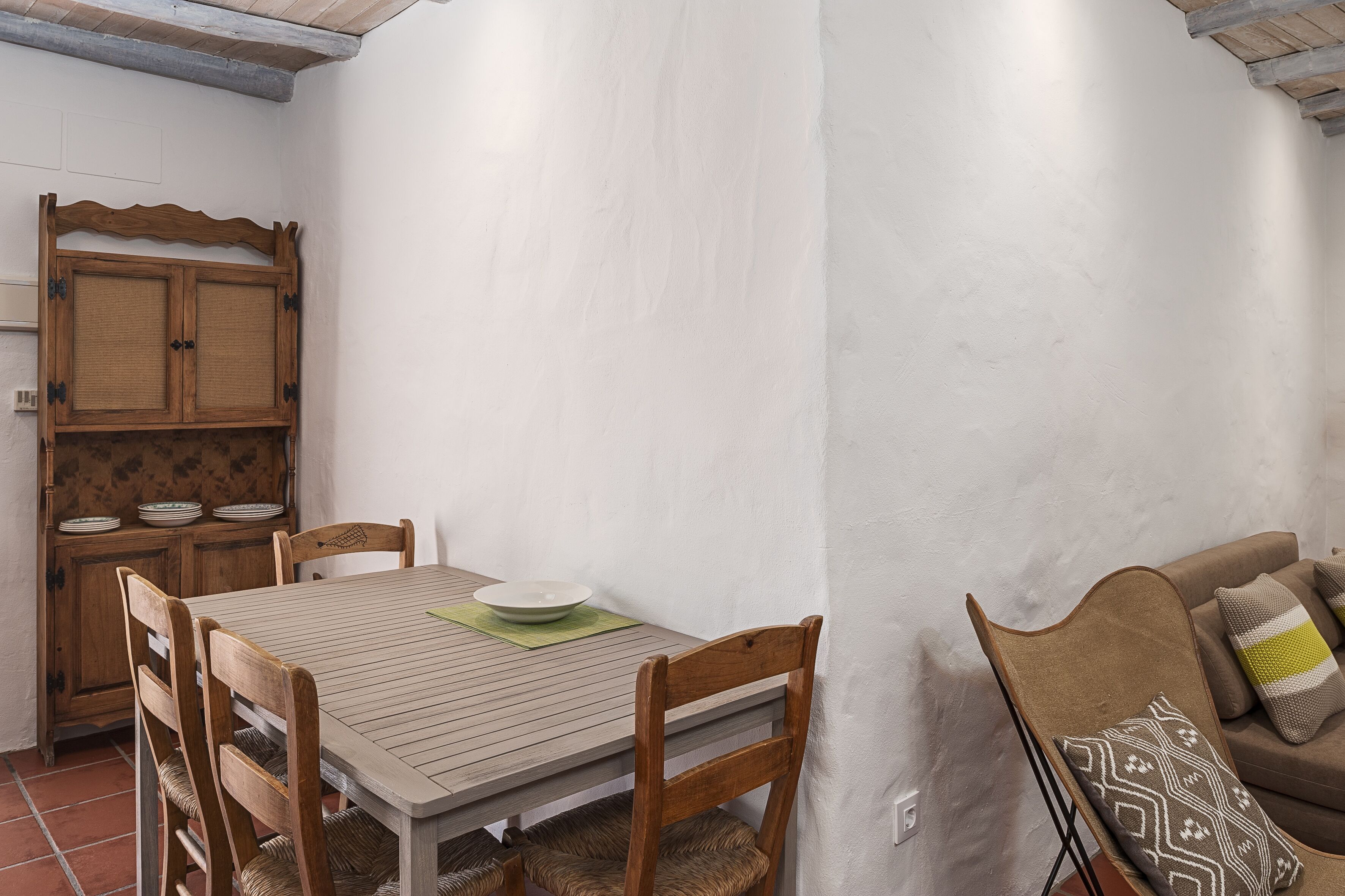 Un comedor con una mesa de madera, sillas y un armario con vajilla.