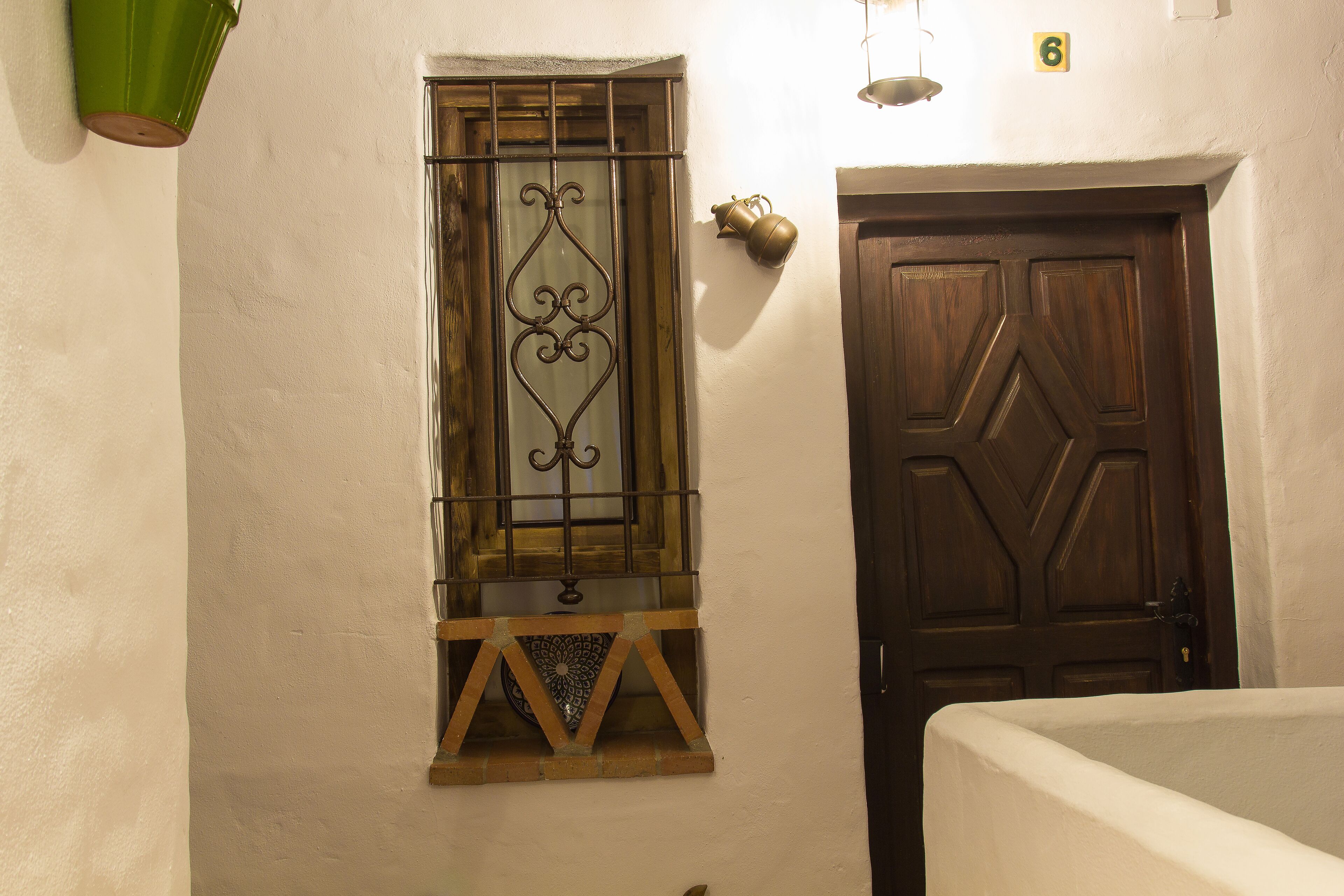 A room with a wooden door and a window with decorative metal bars.