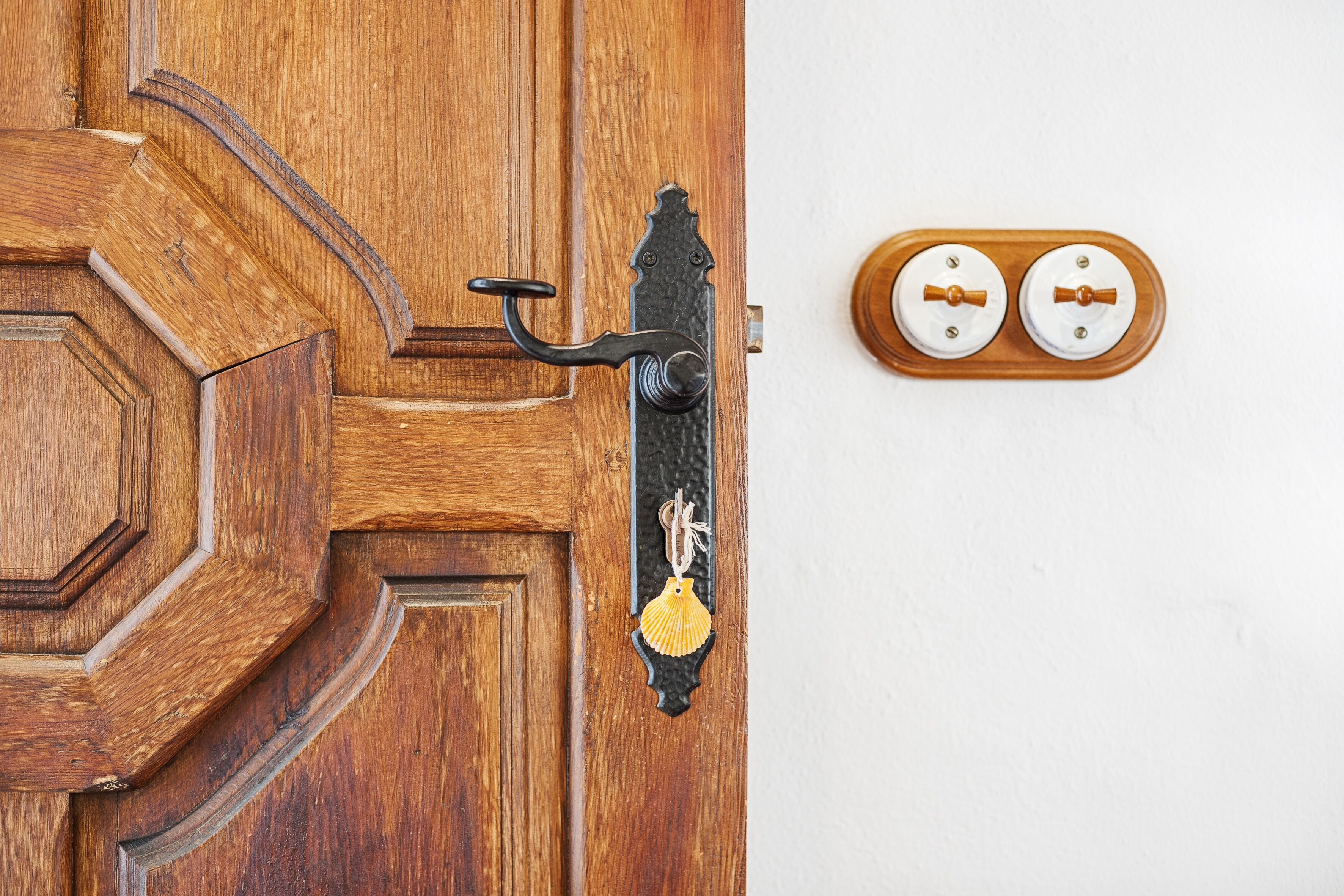 Une porte en bois avec une poignée en laiton et un motif décoratif en forme de coquillage.