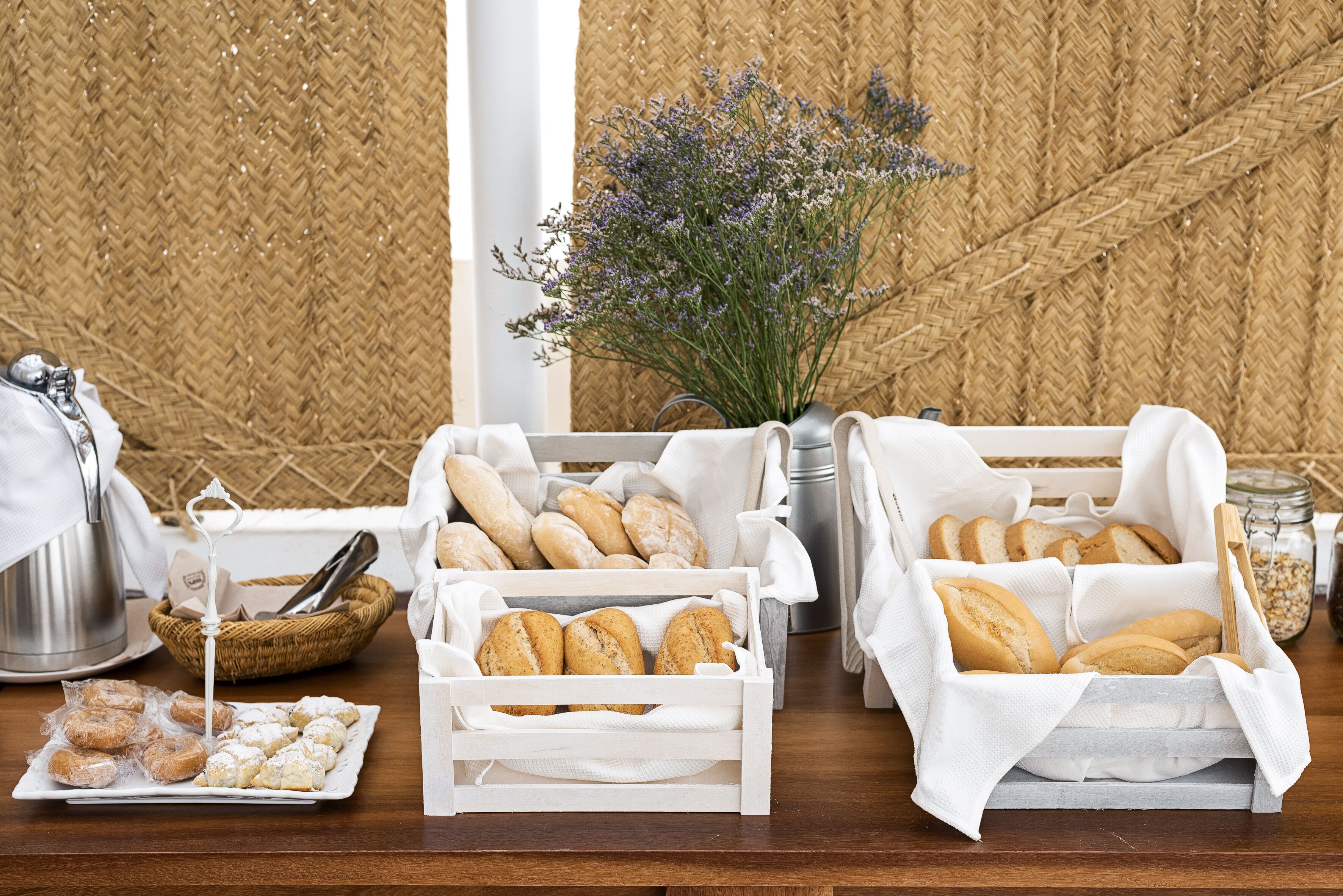 Una mesa con diversos productos de panadería, incluyendo pan y pasteles, dispuestos en cestas blancas y una bandeja.