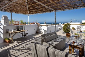 A rooftop terrace with a wooden table, seating, and potted plants. - La Jabega by Conil Home (Conil de la Frontera)