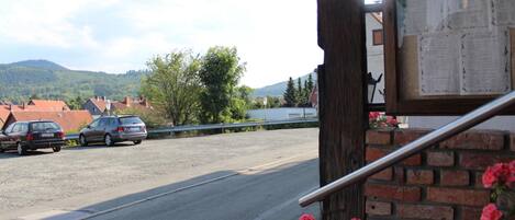 A parking area with cars, a brick wall, and a bulletin board.