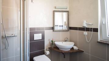 A bathroom with a shower, toilet, sink, and a mirror.