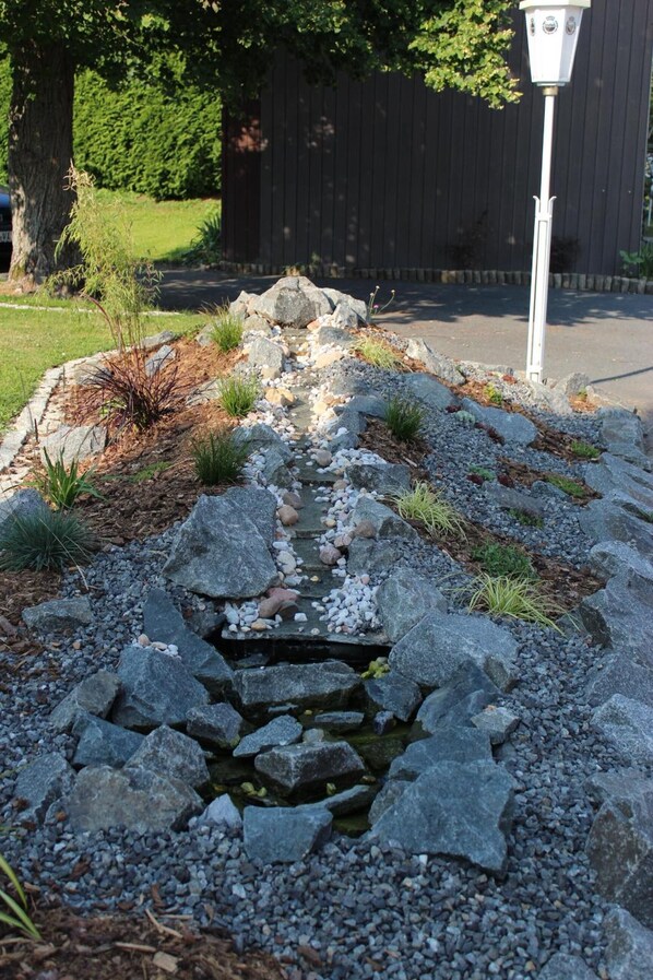 A garden pathway with a small stream, surrounded by rocks and plants. - Hotel Burghagen (Langelsheim)