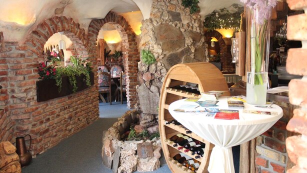 Un interior rústico con paredes de ladrillo, una chimenea de piedra y una bodega.