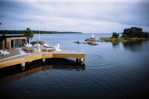 A wooden pier extending into calm water, with lounge chairs and a small building on the left. - Nynäs Havsbad (Nynashamn)