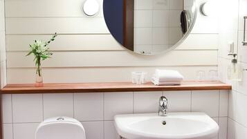 Un baño moderno con inodoro, lavamanos y espejo.