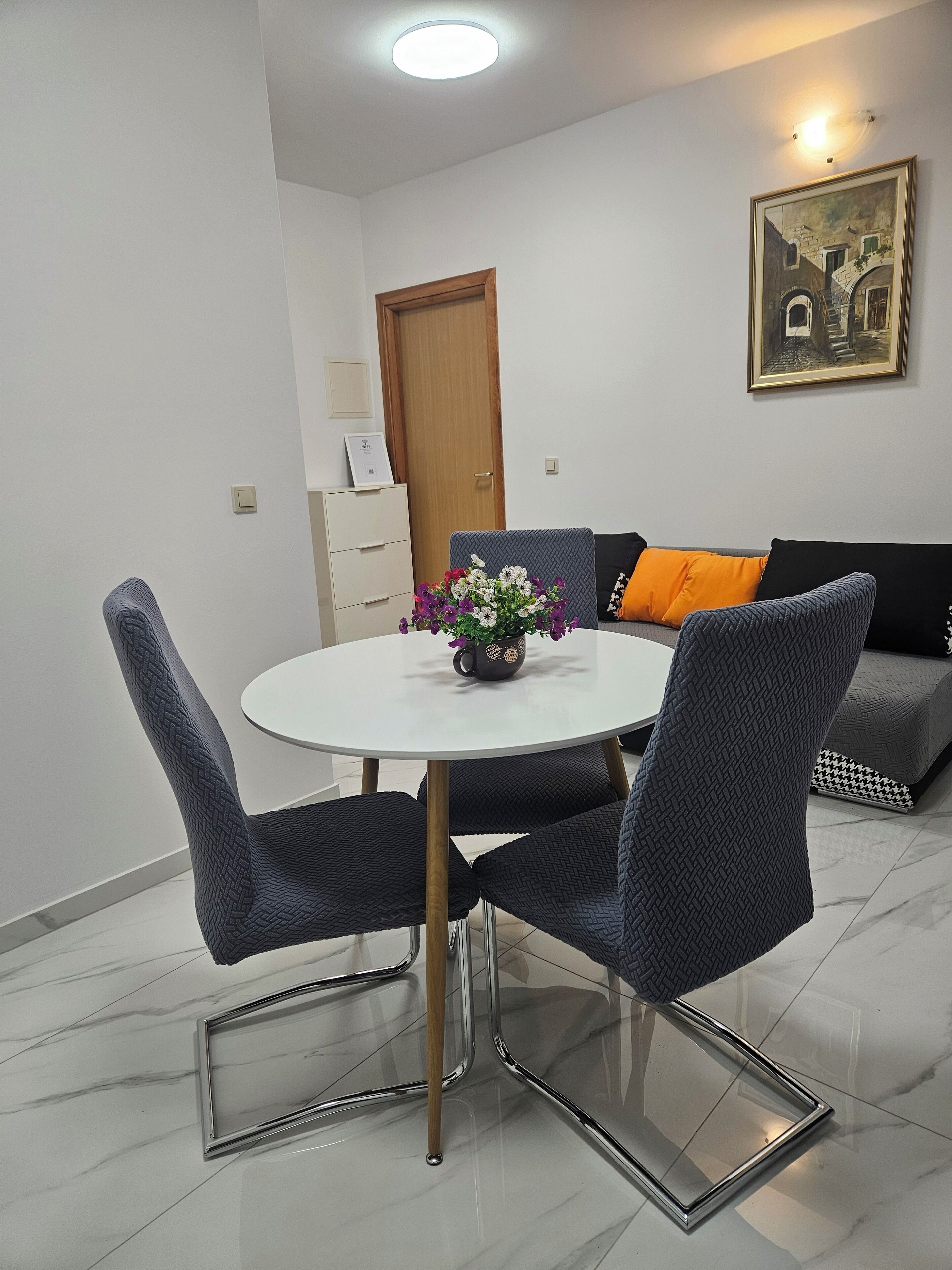 Un coin repas avec une table ronde, quatre chaises et un vase de fleurs.