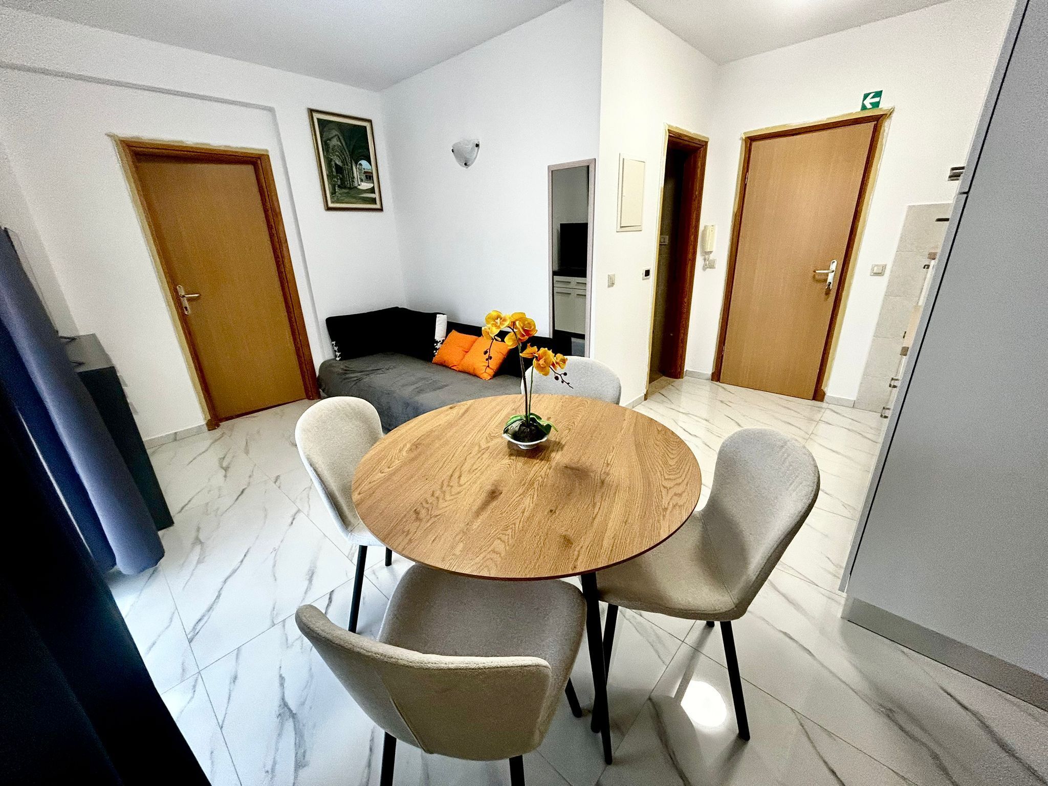A dining area with a round wooden table, four chairs, and a vase with flowers.