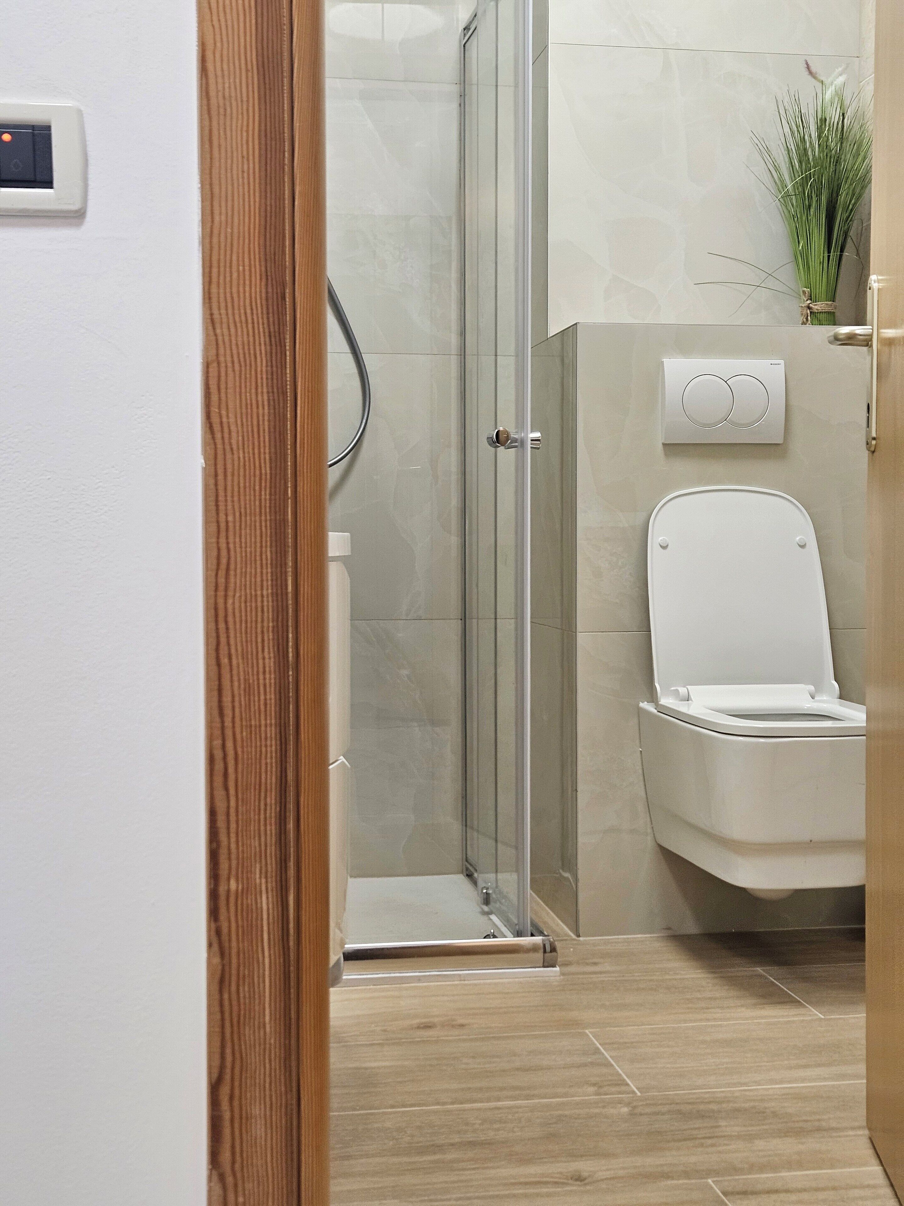 Une salle de bain moderne avec une douche à parois de verre, des toilettes et un bidet fixé au mur.