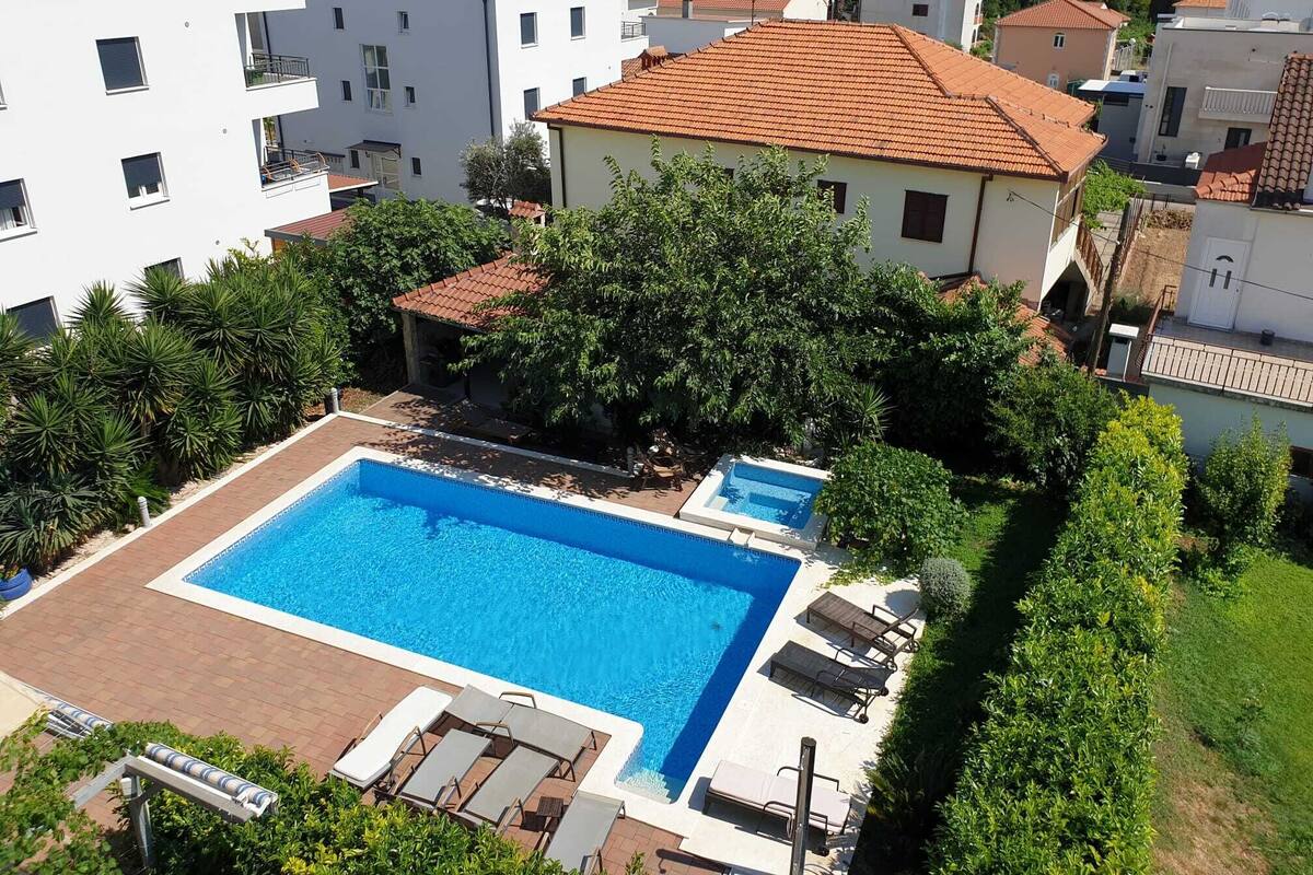 A residential area with a swimming pool surrounded by lounge chairs and greenery.