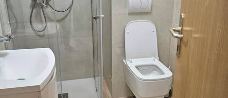 A modern bathroom with a glass-enclosed shower, a white toilet, and a sink.
