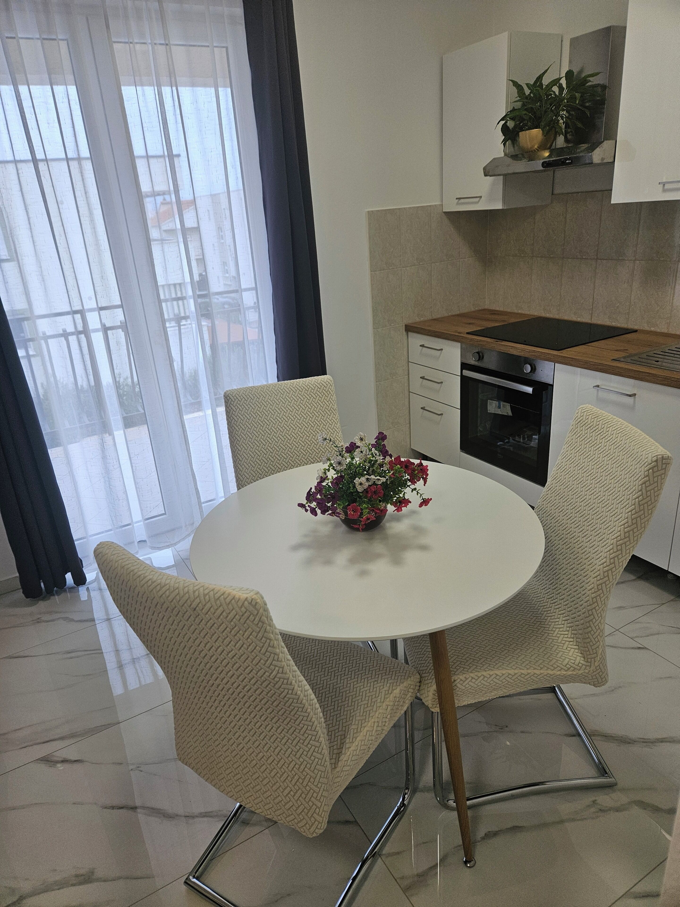 A modern kitchen with a round dining table, four chairs, and a built-in oven.