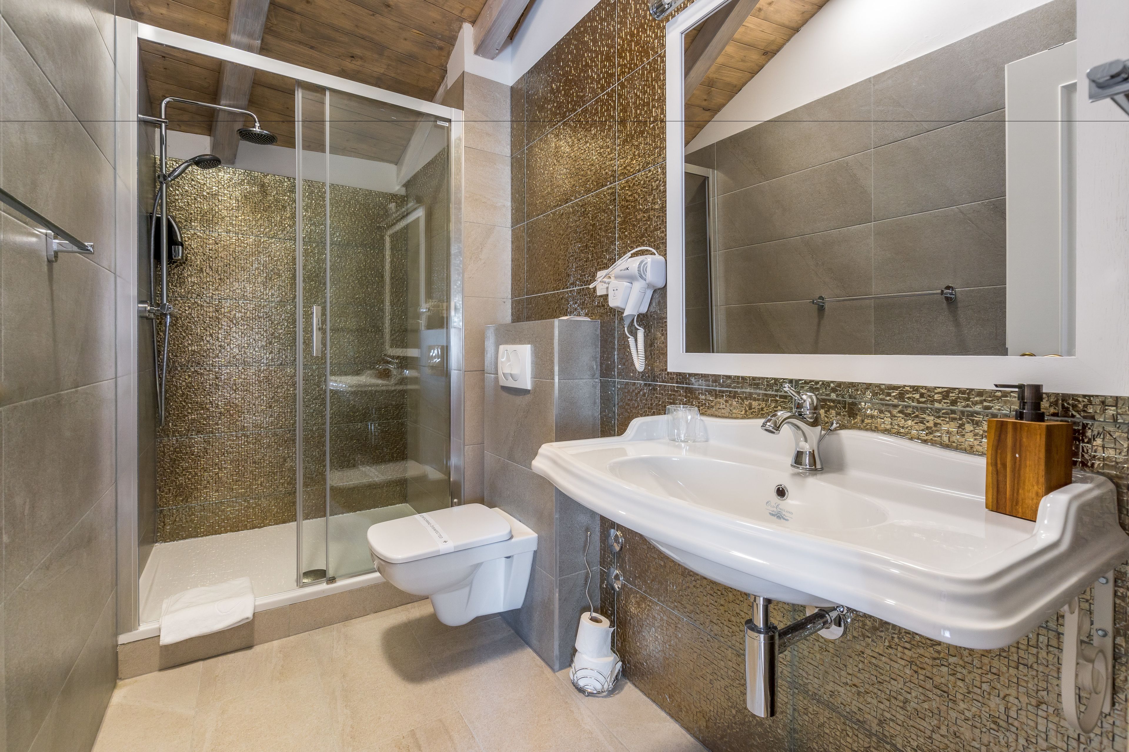 A modern bathroom with a glass-enclosed shower, a white sink, and a toilet.