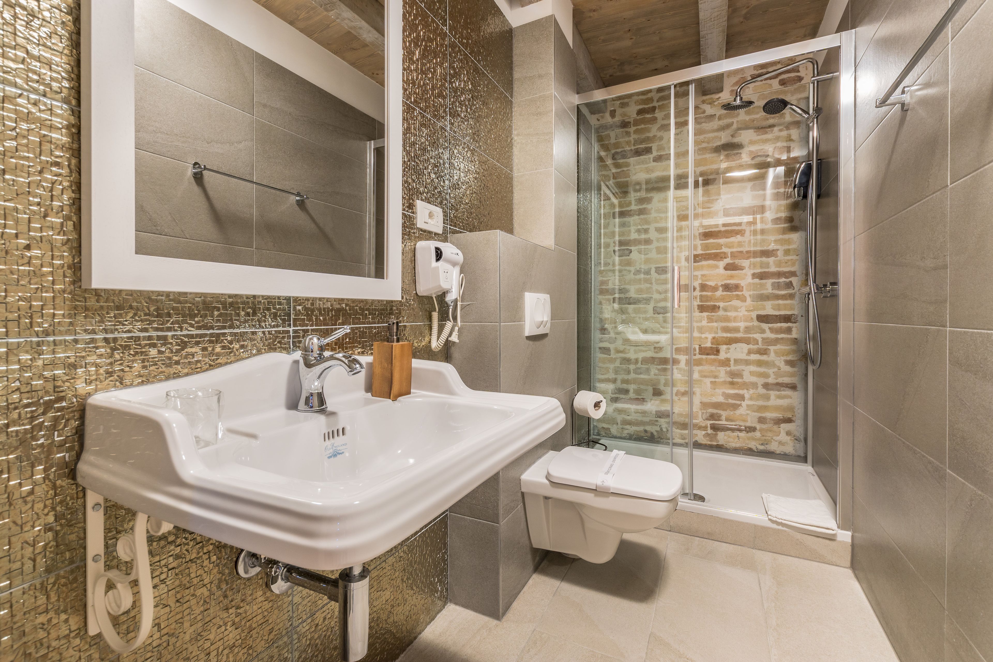 Un baño con un lavamanos grande, un espejo, cabina de ducha de vidrio y un inodoro.