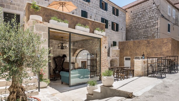 A stone building with a glass entrance, outdoor seating, and potted plants. - Heritage Palace Varos - MAG Quaint & Elegant Boutique Hotels (Split)