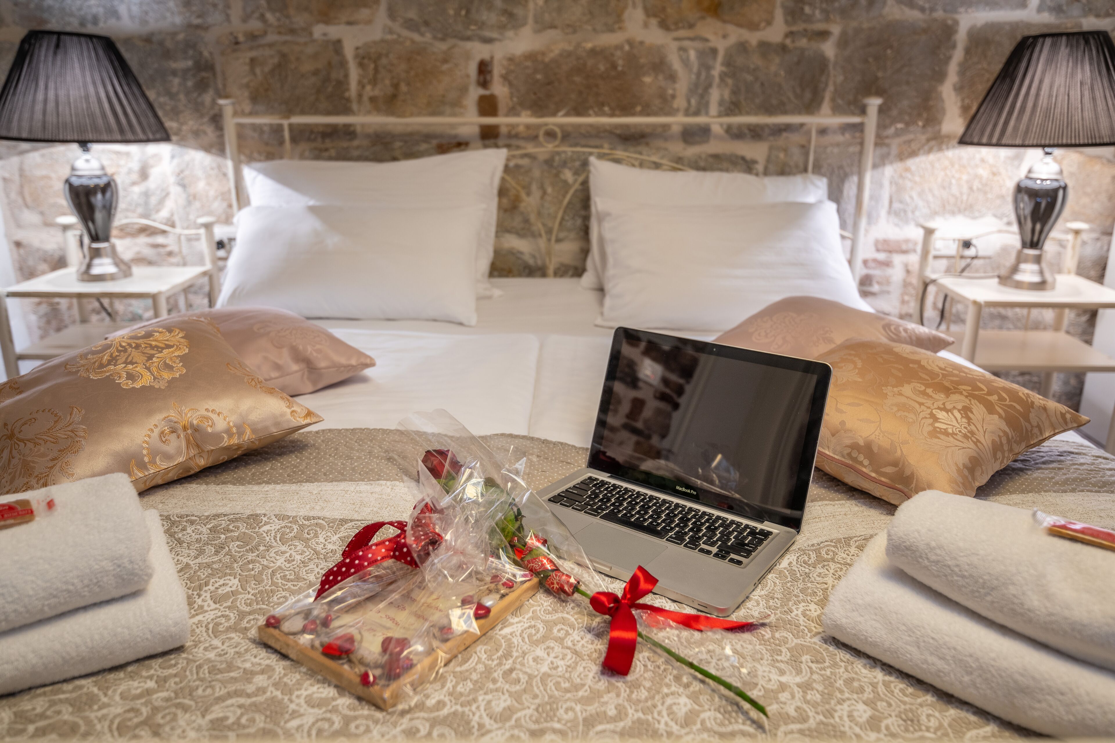 Una habitación de hotel con una cama, una computadora portátil y un ramo de flores.