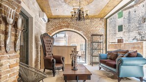 A cozy interior with a brick wall, a wooden table, a blue sofa, and a leather armchair. - Heritage Palace Varos - MAG Quaint & Elegant Boutique Hotels (Split)