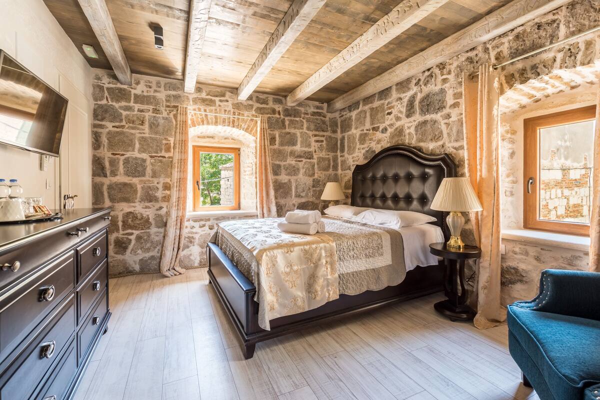 Ein Schlafzimmer mit Stewand, einem Bett mit Kopfteil, einer Kommode, einer Lampe und einem Fenster.