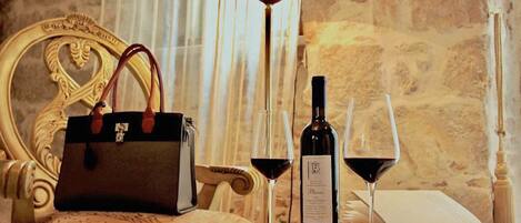 A luxurious setting with a marble table, a bottle of wine, two wine glasses, a handbag, and an open book.