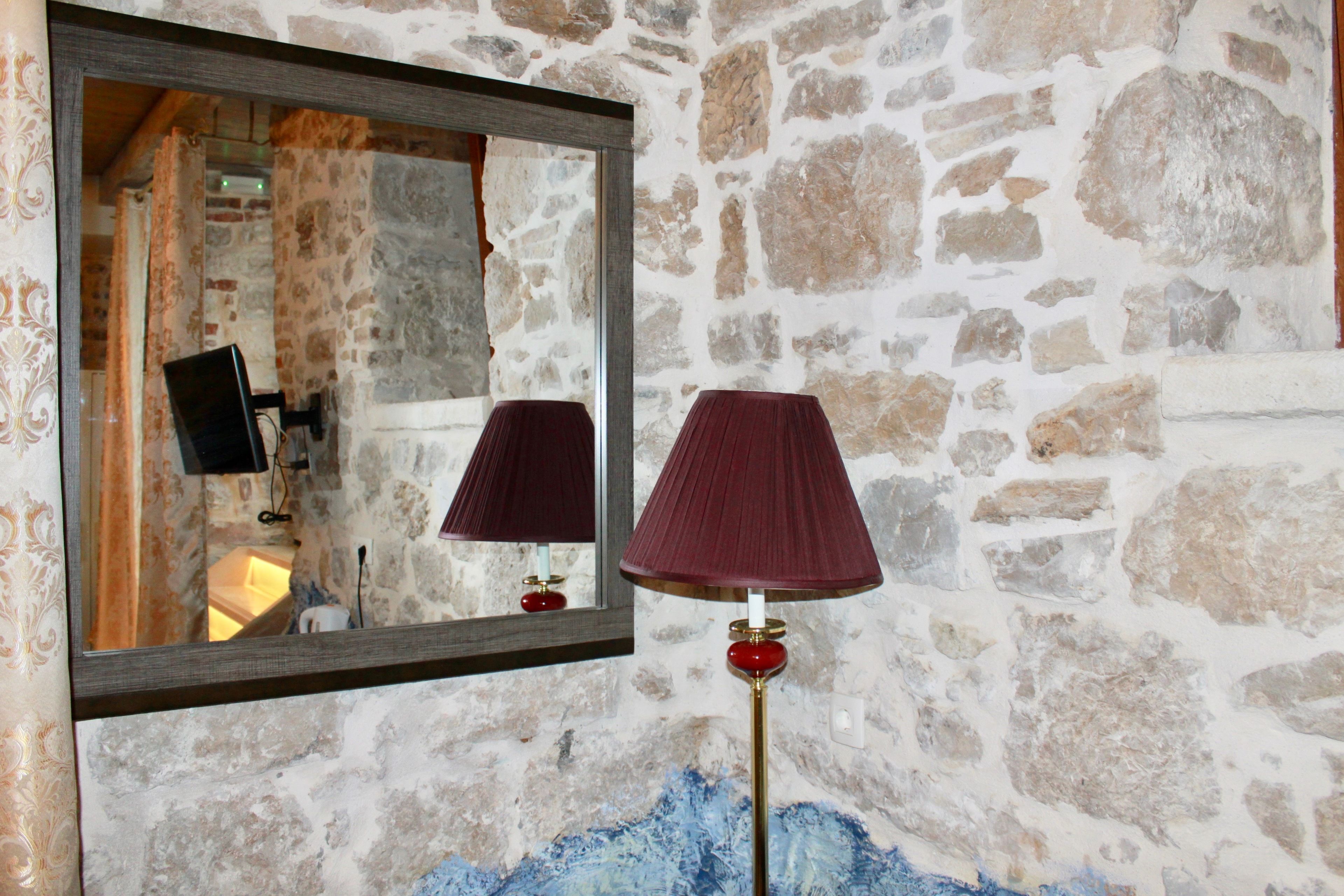 A stone wall with a mirror and a lamp.