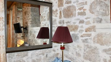 A stone wall with a mirror and a lamp.