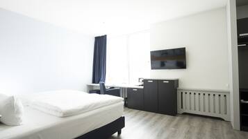 Ein modernes Hotelzimmer mit Bett, Schreibtisch und Kleiderschrank.