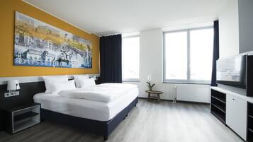 Een moderne hotelkamer met een groot bed, een schilderij van Düsseldorf aan de muur, een televisie en een groot raam.