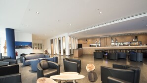 Een moderne lobby met lederen zitplaatsen, een bar en een grote pilaar met een stadsgezichtsmural.