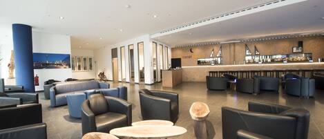 Eine moderne Lobby mit Ledersitzmöglichkeiten, einer Bar und einer großen Säule mit Stadtansicht-Wandgemälde.