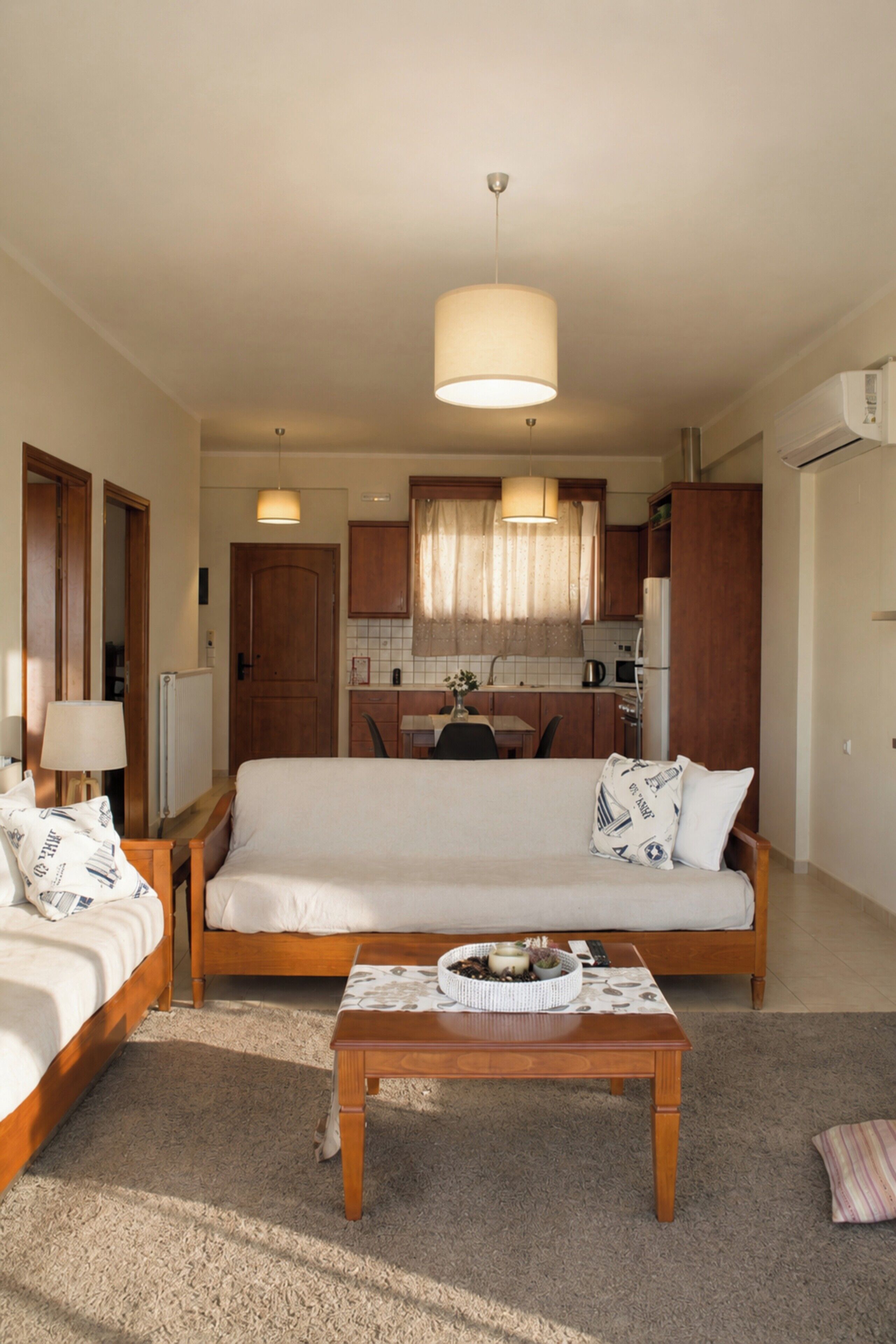 A compact living space with a sofa, a coffee table, a dining table, and a kitchenette.