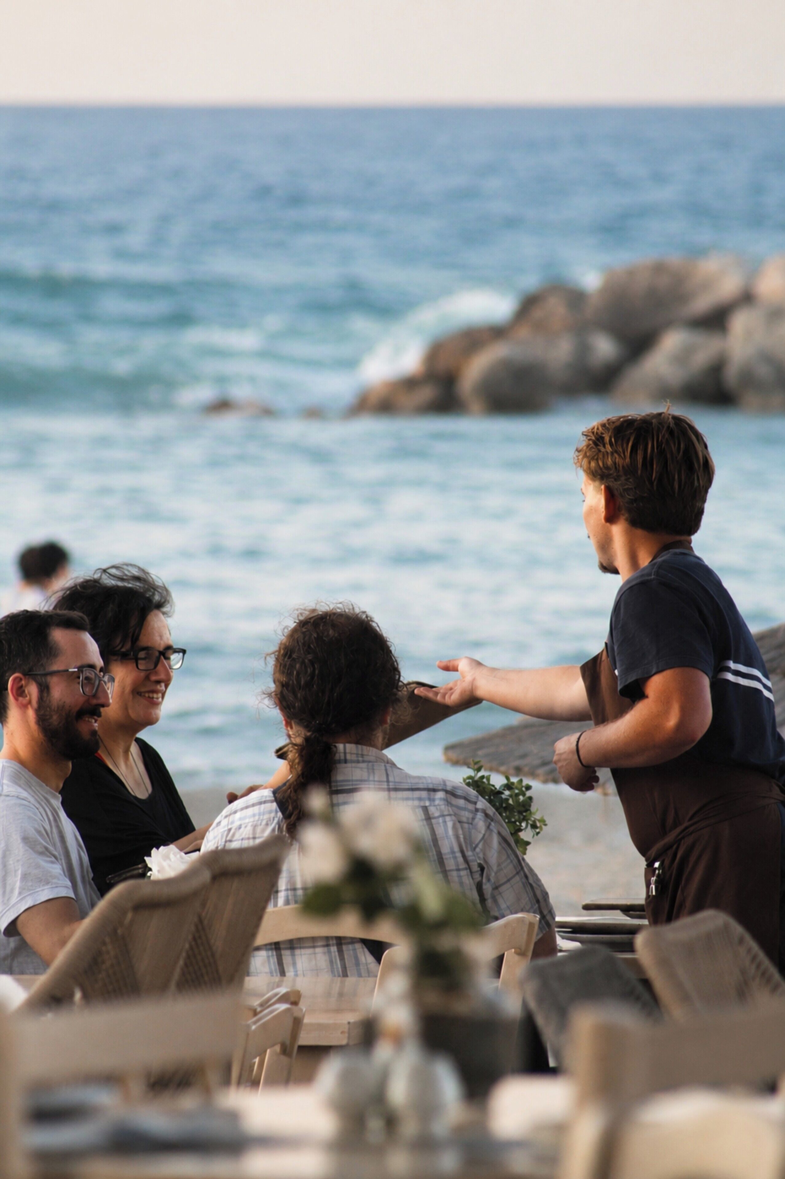 A beachside dining area with chairs and tables, overlooking the ocean.