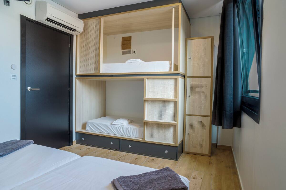 A room with a bunk bed, a wardrobe, and a bed.