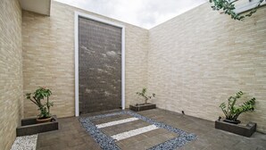 A courtyard with a tiled floor, a central pathway, and potted plants. - RedDoorz Plus @ Cideng Barat (Jakarta)