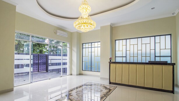 A spacious lobby with a large chandelier, a reception desk, and a view through the glass doors. - RedDoorz Plus @ Cideng Barat (Jakarta)