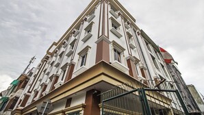 A multi-story building with a symmetrical facade, large windows, and a prominent entrance with a metal gate. - RedDoorz Plus @ Cideng Barat (Jakarta)