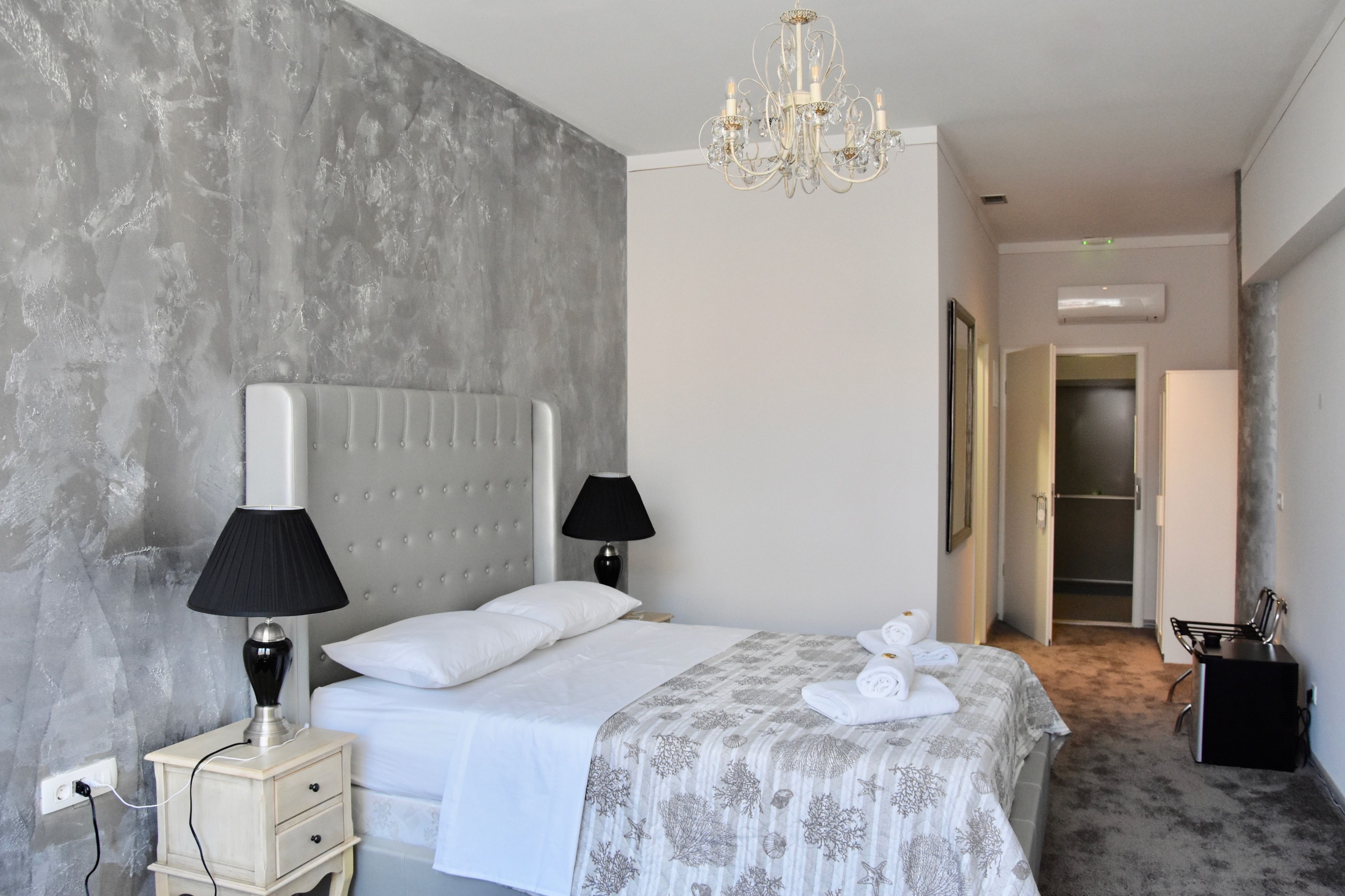 A hotel room with a large bed, two bedside lamps, a chandelier, and a walk-in closet.