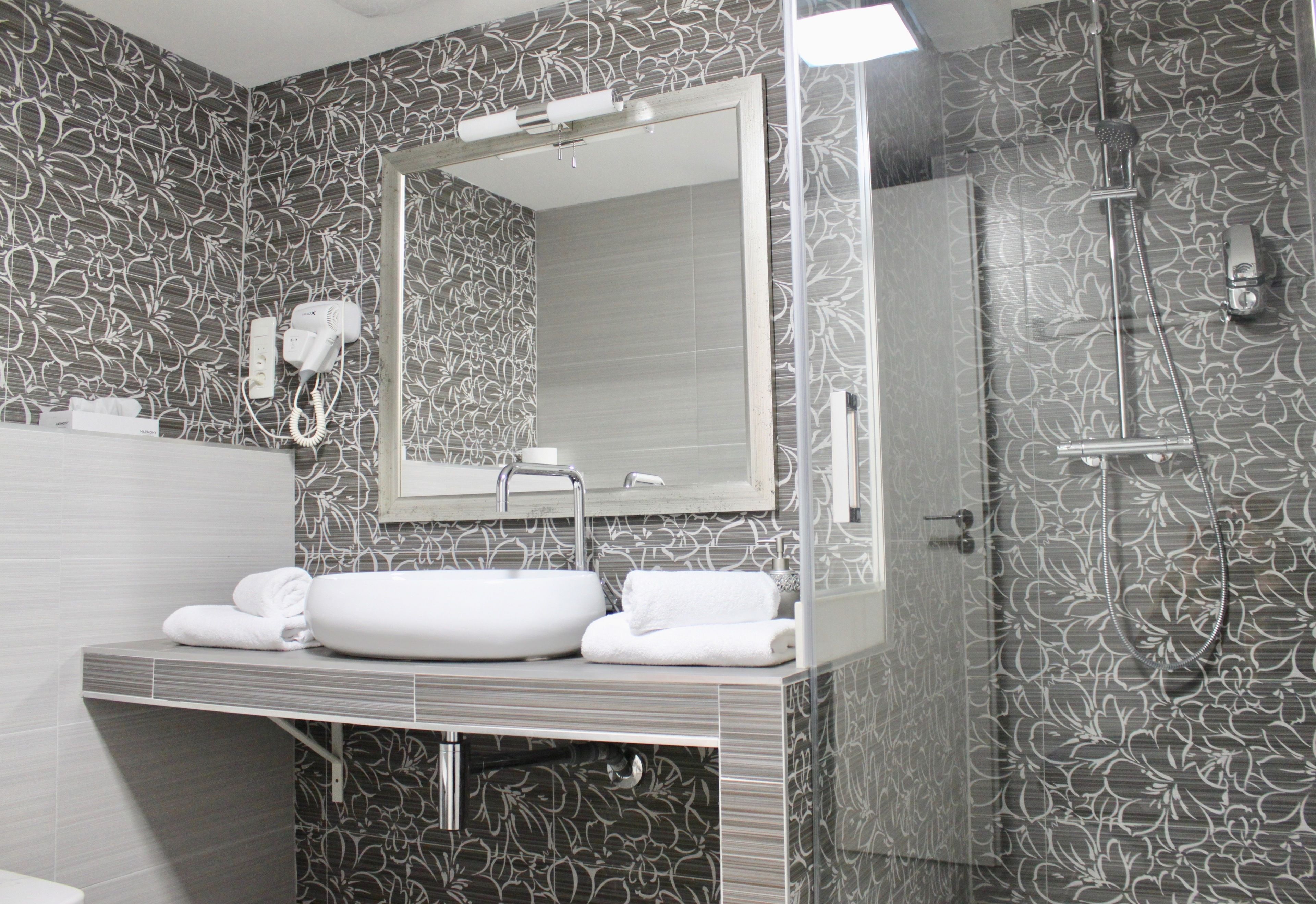 Un baño moderno con un espejo grande, un lavabo y una ducha.